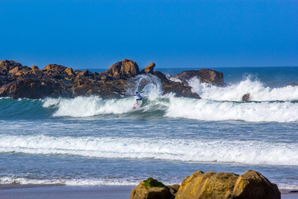 A lone surfer walks along Matosinhos Beach in Portugal